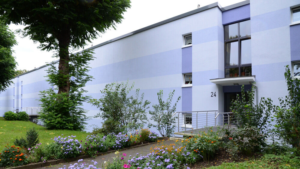 Hausfassade eines Mehrfamilienhauses mit breiten horizontalen Streifen in hellen Flieder Tönen
