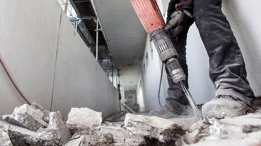 Bauarbeiter mit Presslufthammer zerkleinert Beton
